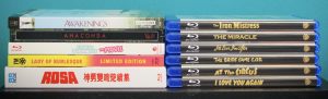 A row of Blu-ray and DVD cases stacked horizontally, showing assorted film titles with both English and foreign language covers visible.