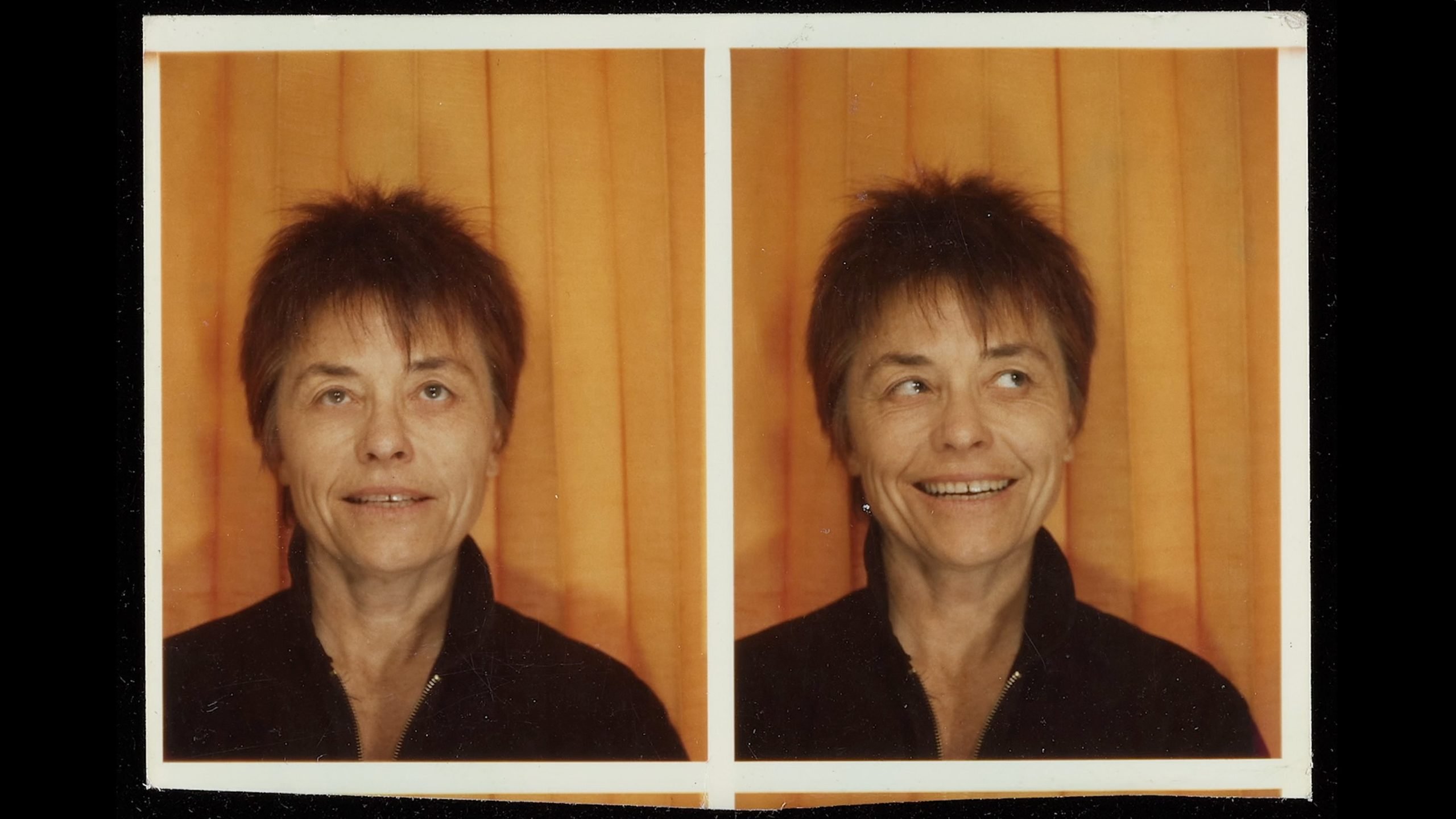 Two photo booth portraits of the same person with short brown hair, wearing a dark top, in front of an orange curtain; one facing forward, the other turned sideways, both with neutral expressions.