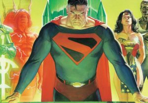5 Comic Book Storylines We Would Love To See Adapted Into Live-Action Films A determined superhero in a red and black "S" costume stands at a table, flanked by other heroes in colorful outfits, against a green and yellow background.