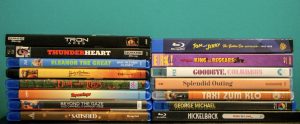A stack of assorted Blu-ray and Ultra HD movie cases arranged vertically against a teal background.