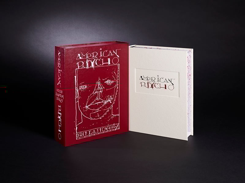 A red slipcase and a white hardcover edition of "American Psycho" by Bret Easton Ellis, displayed standing against a dark background.
