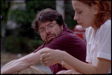 A woman tending to an elderly man's arm outdoors in a caring moment.