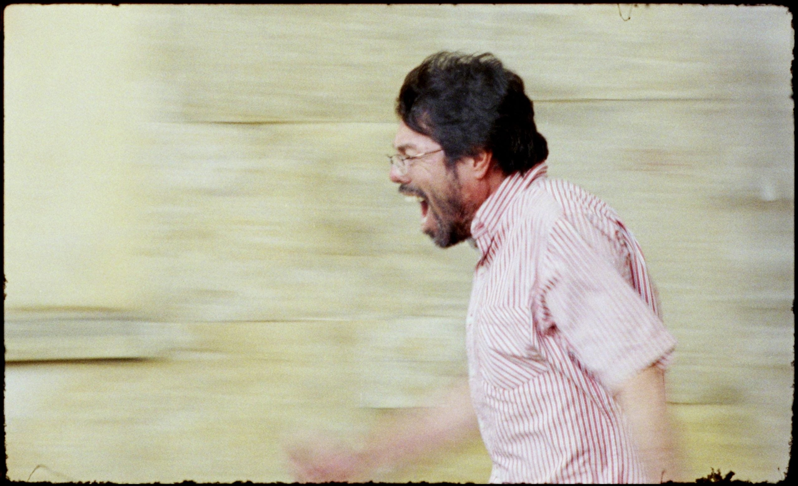 A man with glasses and a beard running happily outdoors.