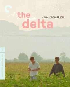 Two young men walk through a green field under a hazy sky. The text reads "the delta, a film by ira sachs," with Criterion Collection branding on the left side.