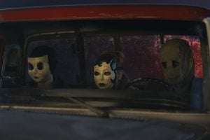 Lionsgate To Release Second & Third Chapters Of ‘The Strangers’ On 4K UHD Blu-Ray This November Three people wearing eerie masks sit in the front seat of an old vehicle at night, seen through the windshield.