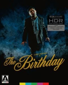 A man in a suit stands amid blue smoke on a movie poster for "The Birthday," starring Corey Feldman, with HDR and 4K Ultra HD features advertised.