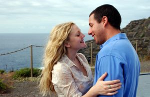 Happy couple embracing outdoors near the coast with cliffs in the background.