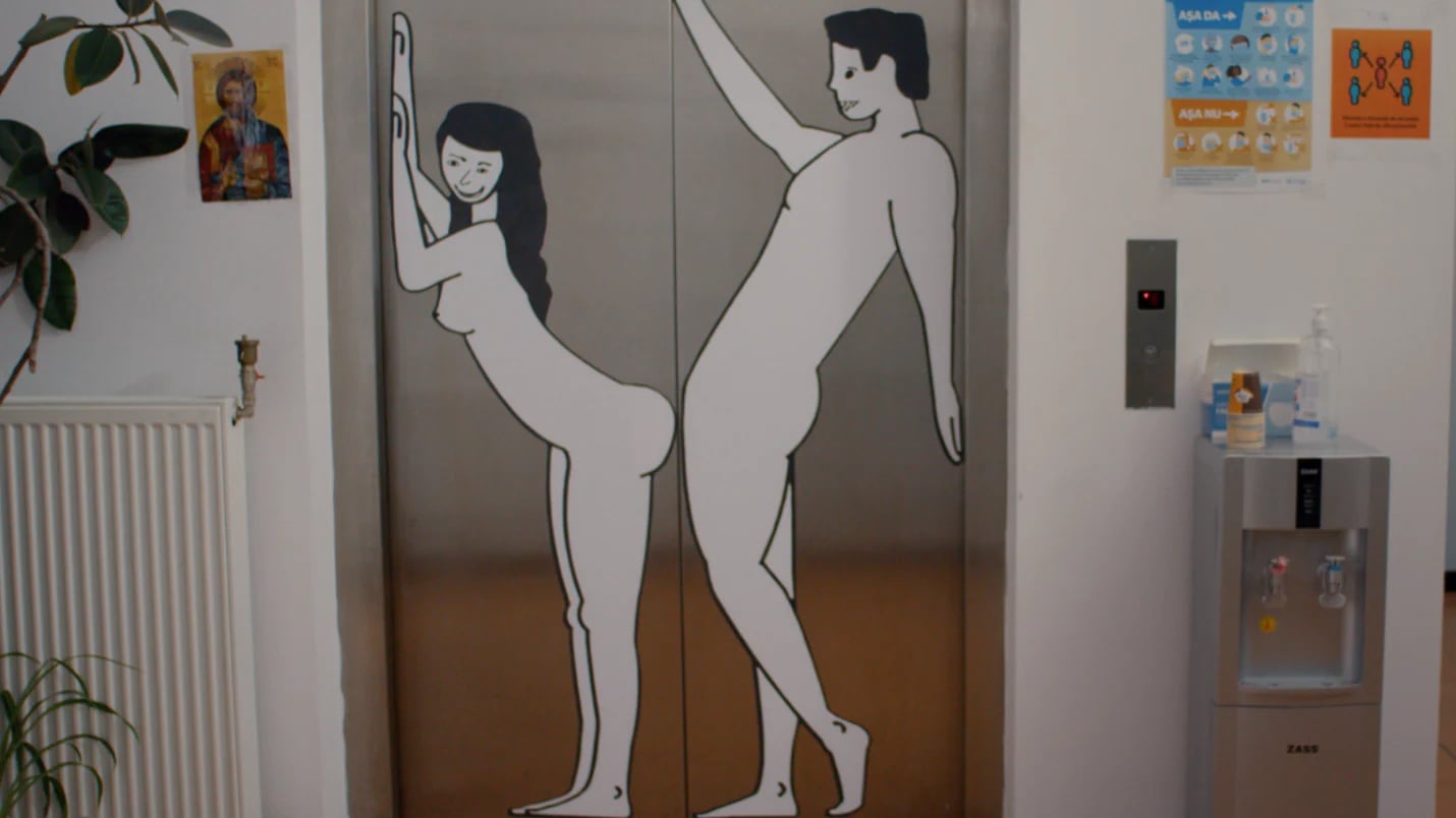 Two elevator doors feature painted outlines of nude male and female figures, positioned so that the doors' opening would separate their bodies.