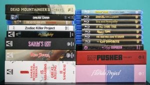 A collection of Blu-ray and DVD movie cases arranged in two stacks, featuring various film titles and box sets, against a blue background.