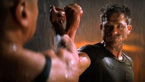 A woman and a man engaged in a fierce arm-wrestling match in the rain outdoors.
