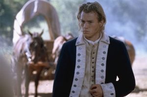 ‘The Patriot’ 4K UHD Blu-Ray SteelBook Review – Glossy Historical Epic Is The Ultimate Dad Movie A young man in a historical military uniform stands in front of a horse-drawn covered wagon, holding his hand to his abdomen with a serious expression.