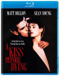 Blu-ray cover of "A Kiss Before Dying" featuring Matt Dillon and Sean Young; Dillon embraces and leans in to kiss Young, with dramatic lighting and bold red film title text.
