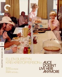 A waitress stands behind a diner counter with food and drinks, while customers sit on stools. The scene is from the film "Alice Doesn't Live Here Anymore.