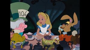 Alice sits at a tea table between the Mad Hatter and the March Hare, surrounded by teapots and teacups in a colorful animated scene from "Alice in Wonderland.