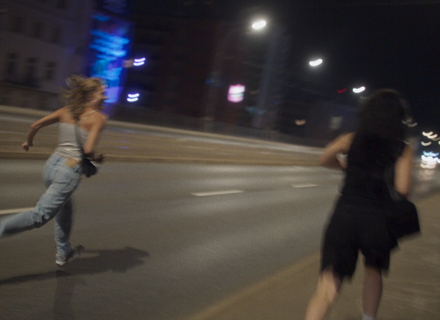 Two people running on an empty city street at night, with blurred motion suggesting movement.