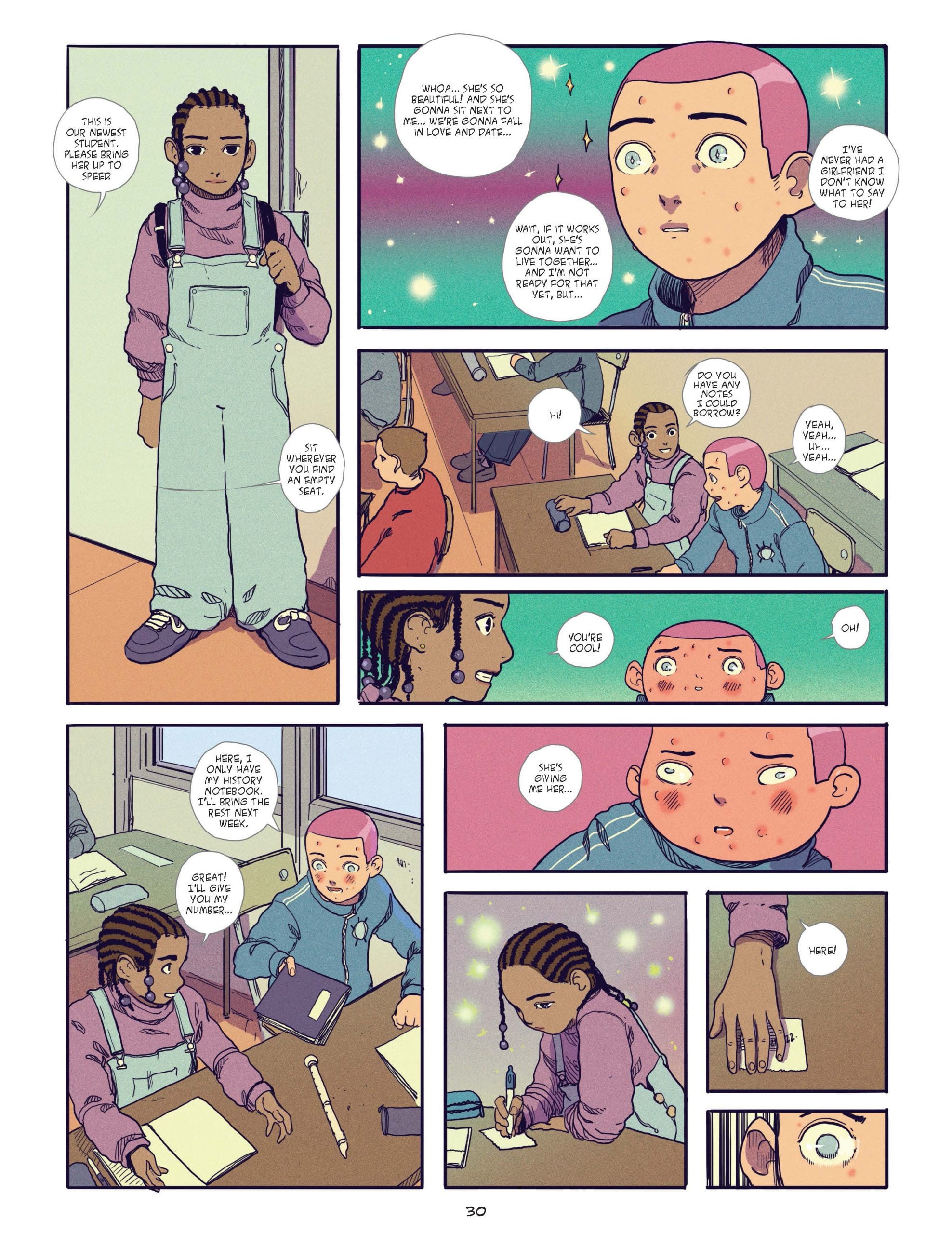 A student with braids and overalls talks to a pink-haired student in class; they interact at their desks while other students work around them.