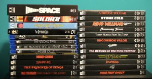 A stack of DVD and Blu-ray movie cases arranged in two columns against a teal background, featuring various film titles such as "Inner Space," "A Bridge Too Far," and "Death Ship.