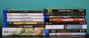 A collection of Blu-ray and DVD movie and TV show cases arranged in two stacks against a teal background.