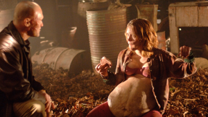 ‘Slither’ 4K UHD Blu-Ray SteelBook Review – A Properly Disgusting Creature Feature From James Gunn A woman with a large, round belly and a man with a beard in a dimly lit, rustic setting.