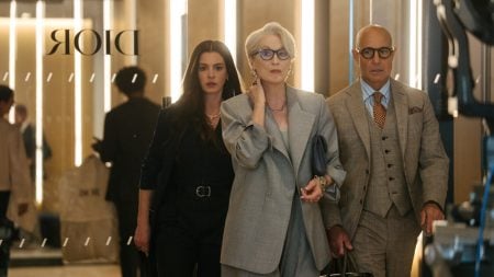 Three people in business attire walk confidently through a modern office lobby with "Dior" reflected on the glass wall behind them.