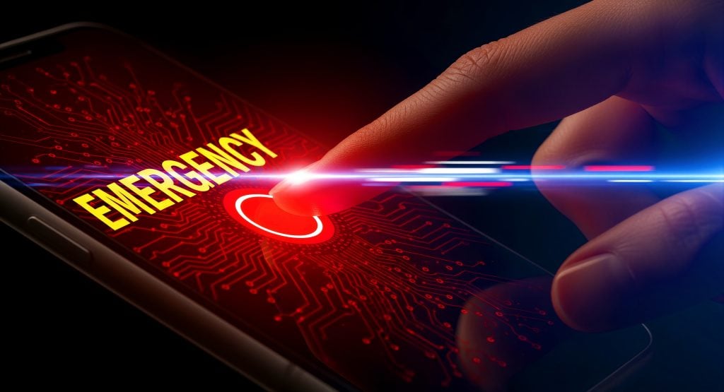 A finger presses an emergency button on a smartphone screen, which displays the word "EMERGENCY" and glowing digital effects.