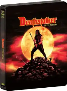 A metal case featuring artwork of a warrior with a sword standing on a pile of skulls before a large, orange full moon; text reads "Deathstalker Triple Feature.