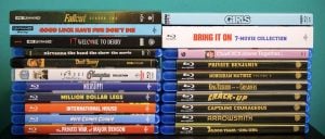 A selection of Blu-ray and 4K Ultra HD movie cases arranged in two stacks, showing various film and TV titles.