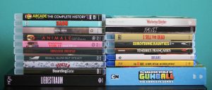 A collection of DVD and Blu-ray cases arranged in two vertical stacks against a teal background, featuring various movie and TV series titles.