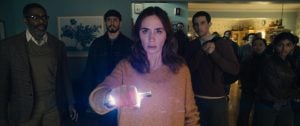 ‘Disclosure Day’ Review – Steven Spielberg Returns To The Blockbuster Space To Remind Us Why He’s One Of Our Best A woman in a beige sweater holds a glowing object, surrounded by a group of people standing in a dimly lit room, all looking ahead with serious expressions.