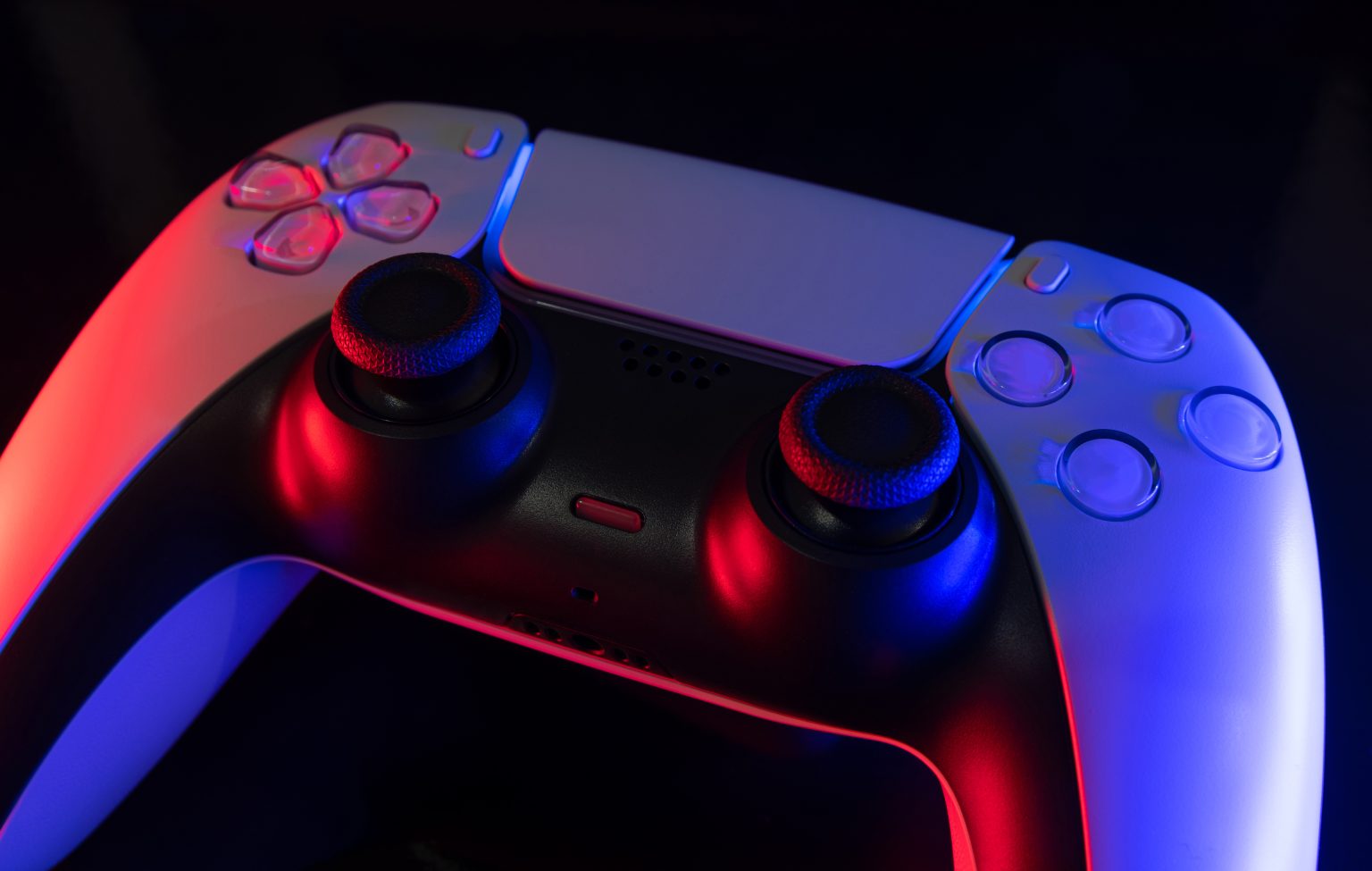 A close-up of a white video game controller lit with red and blue lights against a dark background.
