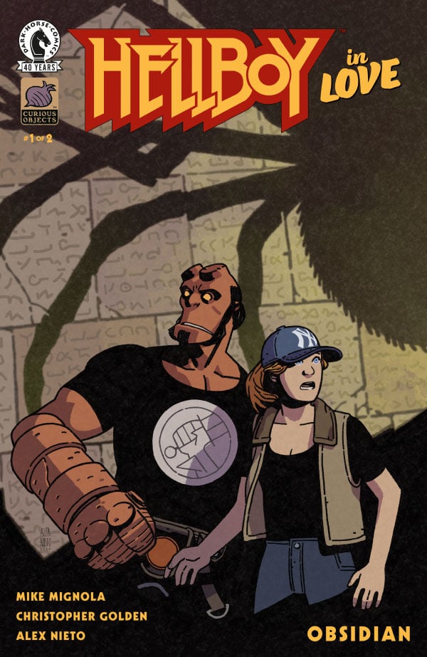 Comic book cover titled "Hellboy in Love: Obsidian" shows Hellboy and a woman standing together, both looking off to the side with serious expressions. A large shadow looms behind them.