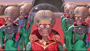 A group of green-suited aliens with large brains, red eyes, and helmets stand in formation; one in front wears a red, glittery cape.