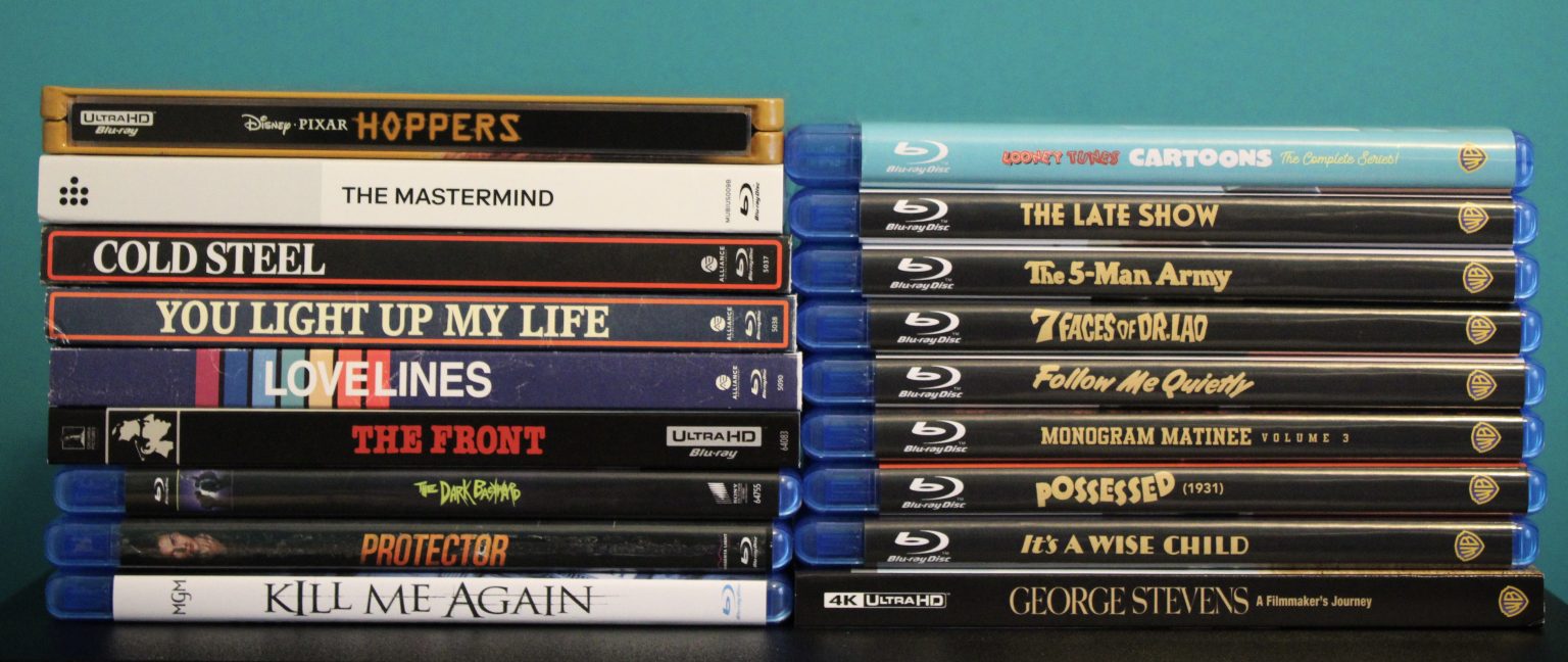 A collection of DVD and Blu-ray movie cases stacked in two columns against a teal background, showing various film titles on their spines.