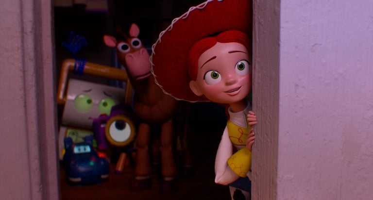 A red-haired doll in a cowboy hat peeks around a doorway, while a horse and several toy characters stand in the background.
