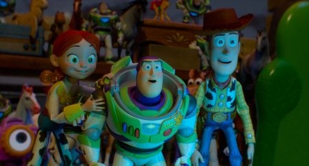 Jessie, Buzz Lightyear, and Woody stand side by side, surrounded by other toys, looking forward with excited expressions.