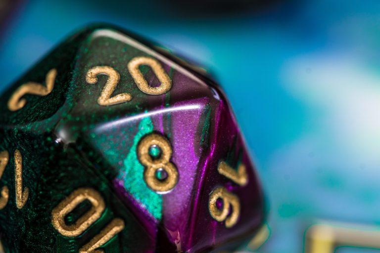 Close-up of a multicolored twenty-sided die showing the numbers 20, 8, 10, and 16, with gold numbering on a blue background.