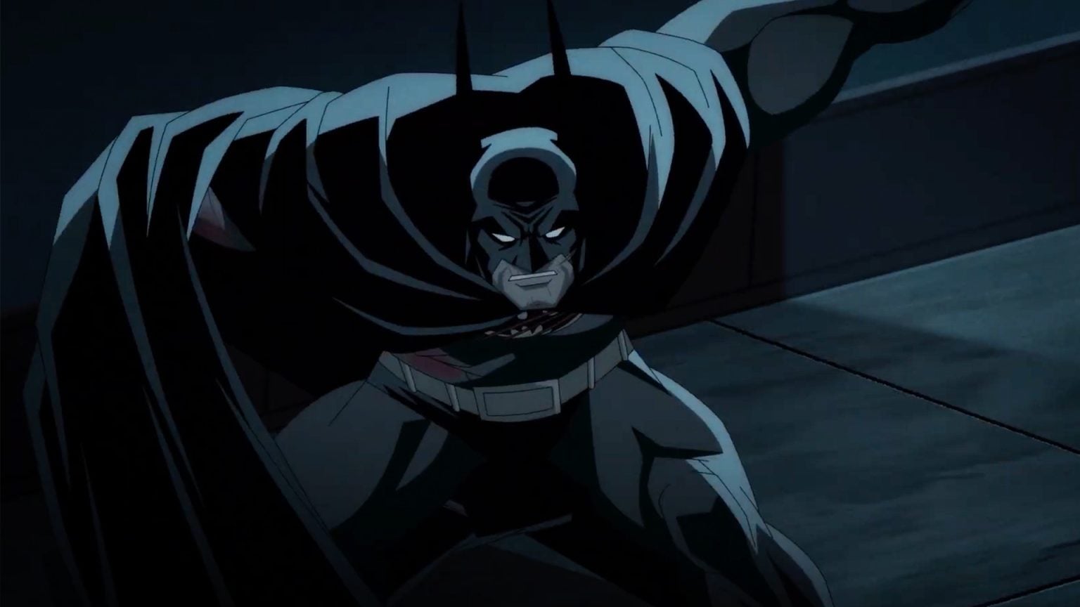 Animated Batman crouches in a defensive stance, cape spread wide, with a serious expression in a dark, shadowy environment.