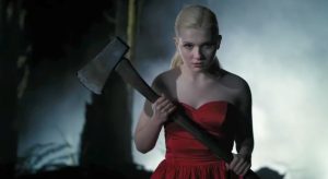 Final Girl (2015) Review – Star Power, Zero Spark A woman in a red dress stands outdoors at night, holding an axe with both hands and looking forward, with mist and trees in the background.