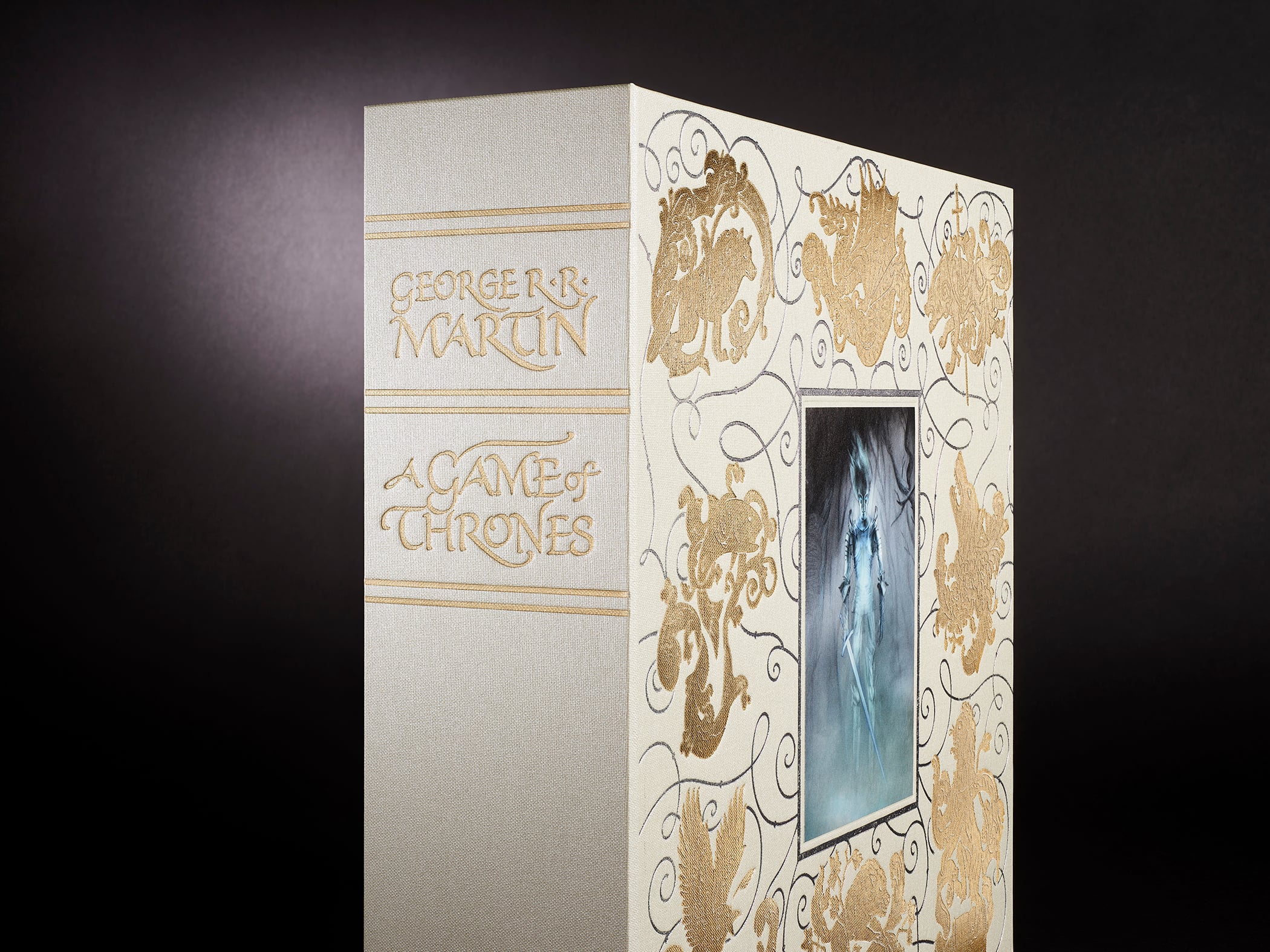 A deluxe edition of "A Game of Thrones" by George R.R. Martin, featuring gold designs and an illustrated cover portrait against a dark background.