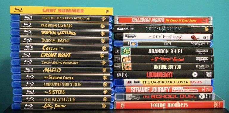Two stacks of Blu-ray and DVD movie cases arranged side by side against a teal background, showing various film titles on their spines.