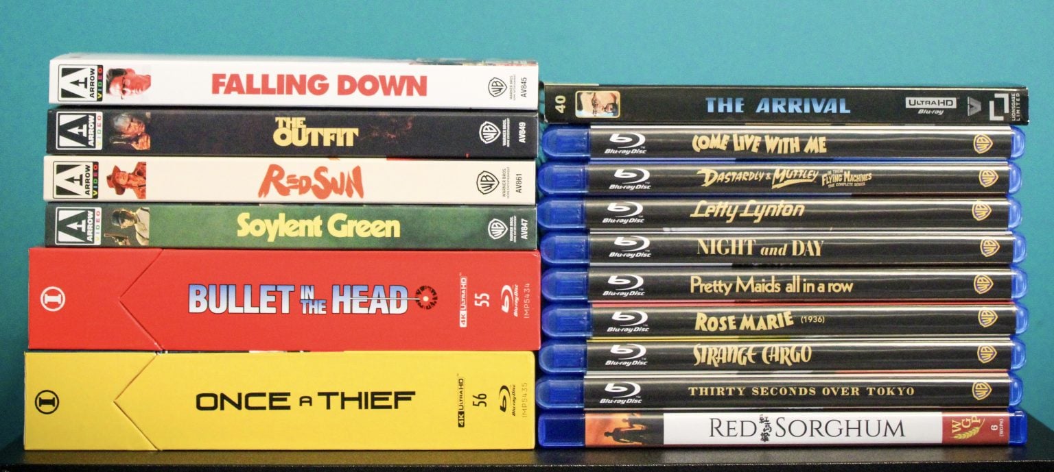 No Streaming Required: Physical Media Spotlight For The Week Of July 7th Eleven DVD cases stacked vertically on the left and ten Blu-ray cases stacked vertically on the right, all with visible movie titles, against a teal background.