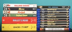 Eleven DVD cases stacked vertically on the left and ten Blu-ray cases stacked vertically on the right, all with visible movie titles, against a teal background.