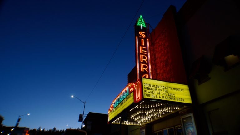 ‘The Last Picture Shows’ Review – A Full-Throated Embrace Of The Local Movie Theater Neon-lit Sierra theater marquee at dusk displays showtimes for "Kingdom of the Planet of the Apes" and "Furiosa: A Mad Max Saga.