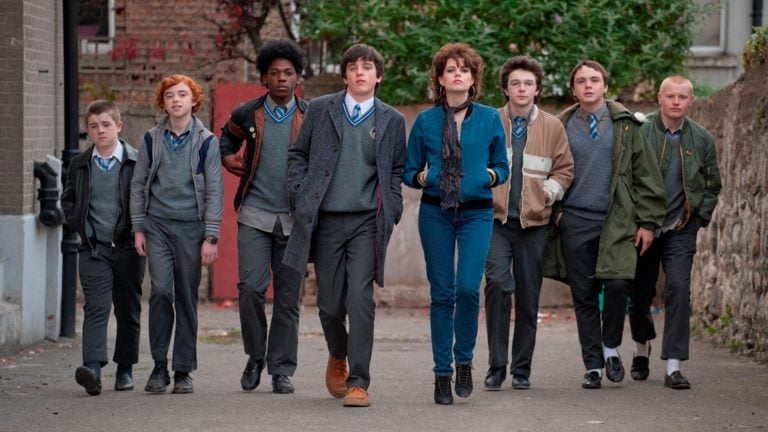 Lionsgate To Release The Music-Driven Coming-Of-Age Favorite ‘Sing Street’ On 4K UHD Blu-Ray A group of teenagers in school uniforms and one girl in casual clothes walk side by side down a street, looking ahead confidently.