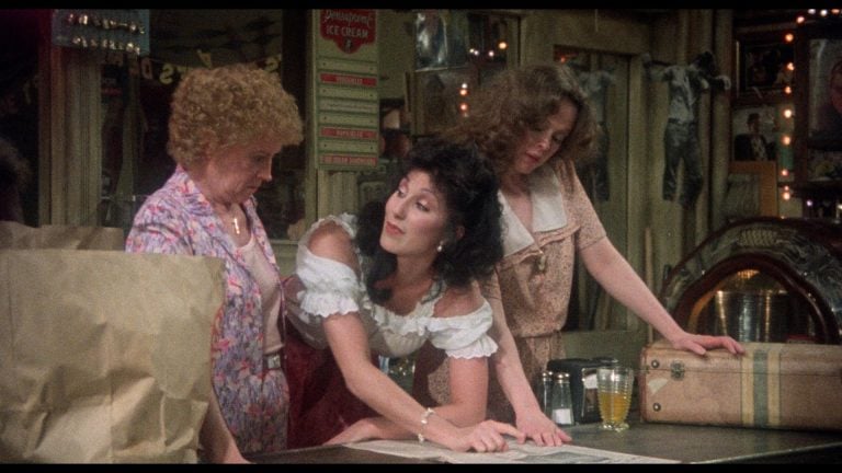 ‘Come Back To The 5 & Dime, Jimmy Dean, Jimmy Dean’ 4K UHD Blu-Ray Review – An Overlooked Robert Altman Gem Three women stand around a counter in a vintage-style store, looking down at a newspaper spread out before them.