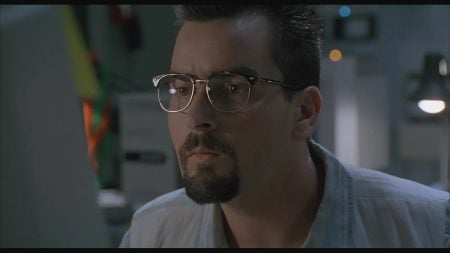‘The Arrival’ (1996) 4K UHD Blu-Ray Review – Charlie Sheen Searches For The Truth In This Engaging Alien Outing A man with glasses and a goatee closely looks at a computer screen in a dimly lit room.