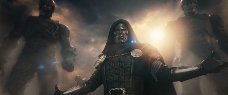 A figure in metal armor and a green cloak stands with arms open, flanked by two large robotic beings, with dramatic lighting and clouds in the background.
