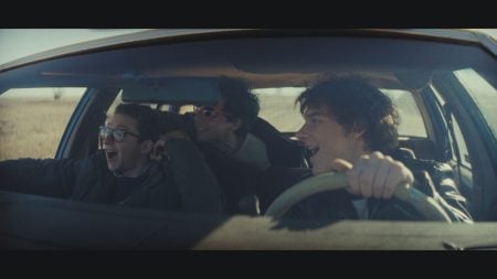 ‘Nimrods’ Review – A Charming if Somewhat Middling Coming-of-Age Comedy Three young men are in a moving car; one drives while the other two ride as passengers. They are smiling or laughing, and sunlight streams in through the windshield.