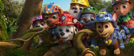 ‘Paw Patrol: The Dino Movie’ Review – A Dino-Sized Adventure Made For Its Youngest Fans A group of animated puppies in colorful helmets and uniforms gather closely together, looking curiously at something off-screen in a jungle setting.