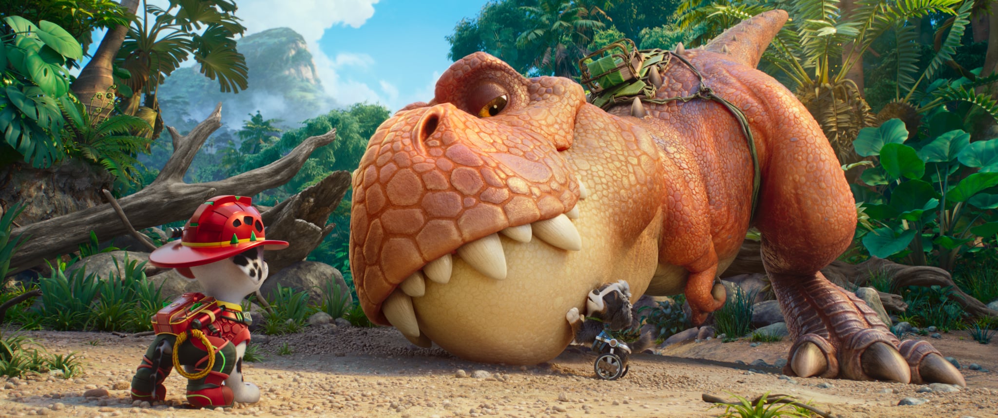 An animated dog in a fire helmet faces a large orange dinosaur lying on the ground, while another dog examines the dinosaur’s mouth in a lush jungle setting.